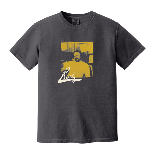 Black Rusty Williams Comfort Colors t-shirt with a printed, stylized yellow-tinted image of a seated man and Ready in white script below.