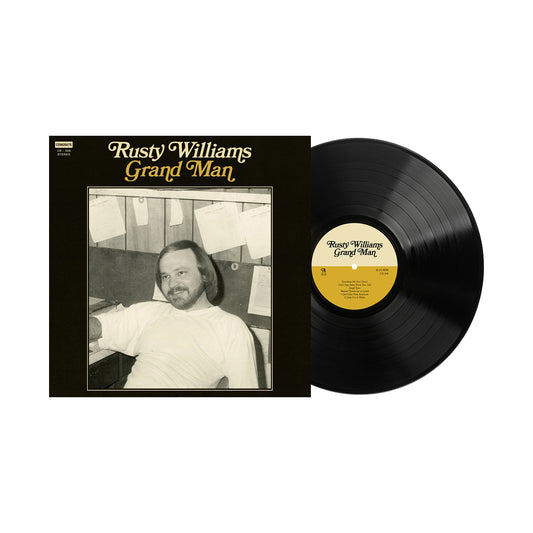 The Rusty Williams vinyl record, titled Grand Man, features a smiling bearded man on the album cover, sitting at a desk with papers on the wall behind him. Now shipping, this release includes a detailed track listing for fans. Brand: Rusty Williams.