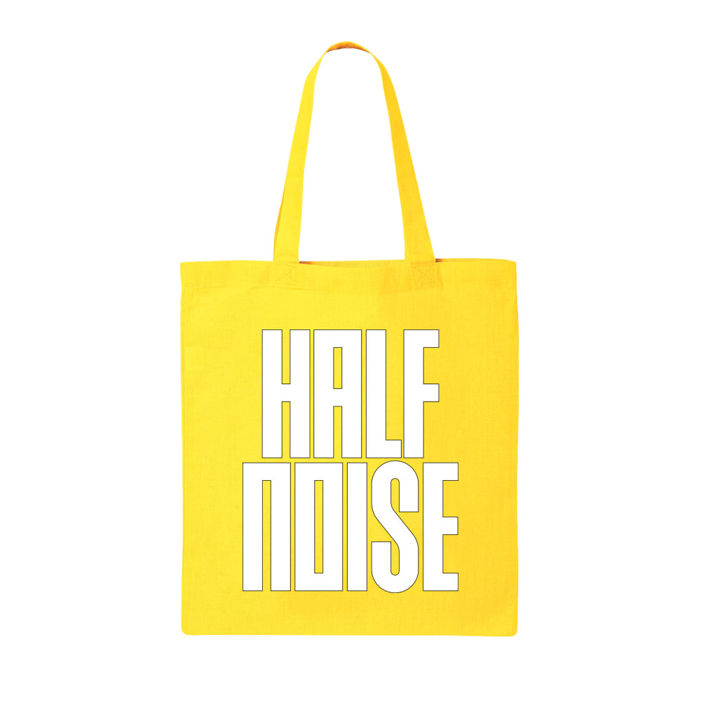 image of a yellow canvas tote bag on a white background. tote has full print in white that says half noise