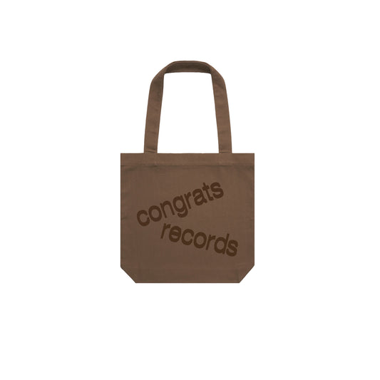 A brown tote bag from Congrats Records with their logo printed diagonally in dark brown on the front, shown on a plain white background.