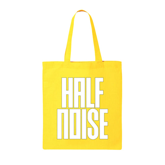 image of a yellow canvas tote bag on a white background. tote has full print in white that says half noise