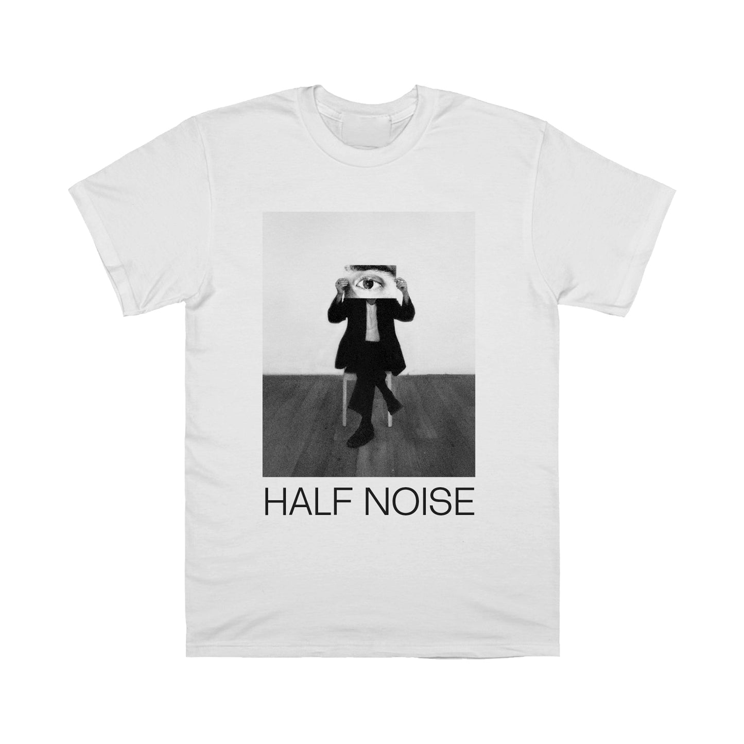 image of the front of a white tee shirt on a white background. the tee has a black and white image of a person sitting cross legged in a chair with a big photo of an eye over their face. the bottom says half noise. 